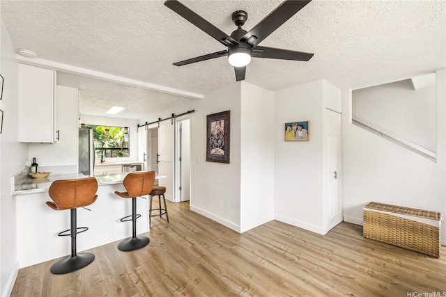 68-037 Apuhihi St Unit B, Waialua, HI 96791 - kitchen featuring a textured ceiling, a barn door, stainless steel appliances, light wood-style flooring, and ceiling fan