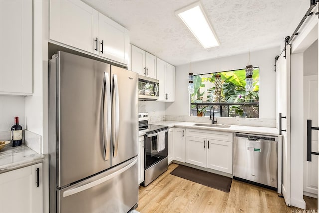 68-037 Apuhihi St Unit B, Waialua, HI 96791 - kitchen featuring appliances with stainless steel finishes, a sink, a barn door, white cabinetry, and a textured ceiling