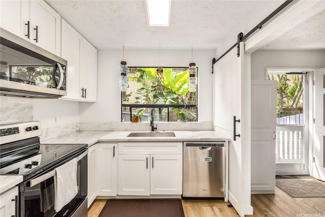 68-037 Apuhihi St Unit B, Waialua, HI 96791 - kitchen featuring stainless steel appliances, a sink, light wood-type flooring, white cabinets, and a textured ceiling