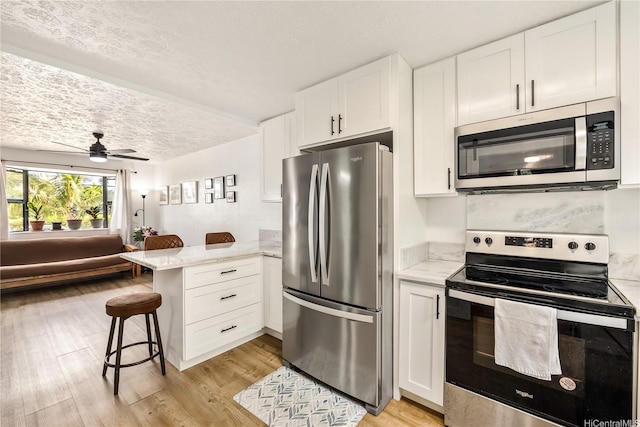 68-037 Apuhihi St Unit B, Waialua, HI 96791 - kitchen with appliances with stainless steel finishes, a peninsula, a textured ceiling, white cabinets, and ceiling fan