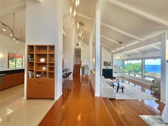 living room with high vaulted ceiling, a notable chandelier, beam ceiling, and a wealth of natural light