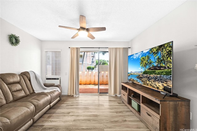 living area with cooling unit, light wood-style floors, ceiling fan, and a textured ceiling