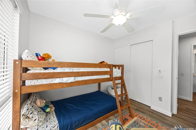 bedroom with ceiling fan, a closet, baseboards, and wood finished floors