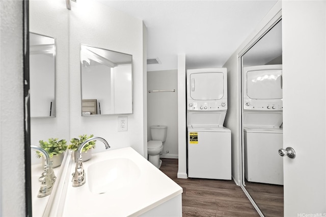 bathroom with toilet, wood finished floors, vanity, and stacked washer / drying machine