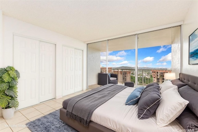 tiled bedroom with a wall of windows, two closets, and access to outside