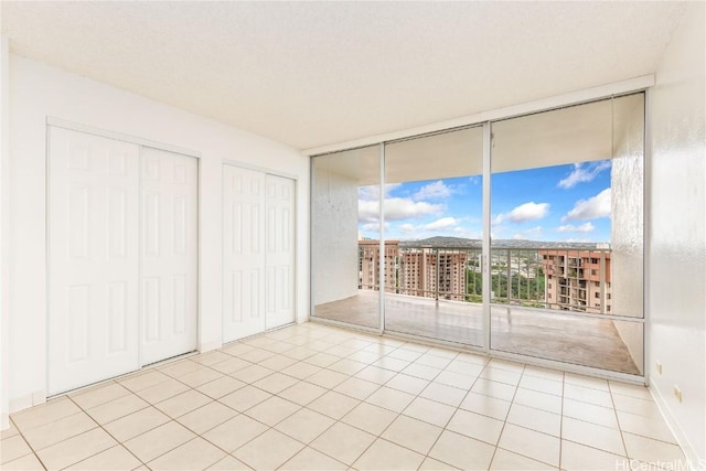 unfurnished bedroom featuring floor to ceiling windows, tile patterned floors, access to exterior, and multiple closets