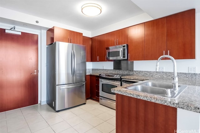 kitchen with light tile patterned flooring, a sink, stainless steel appliances, and brown cabinets
