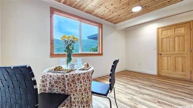 dining space featuring light wood-style flooring, baseboards, crown molding, and wooden ceiling