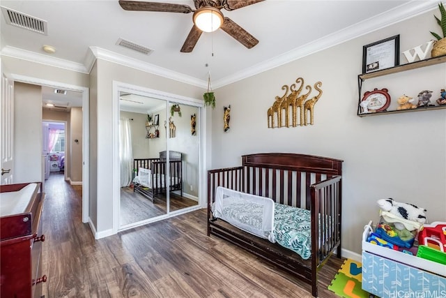 bedroom featuring wood finished floors, baseboards, ornamental molding, and visible vents