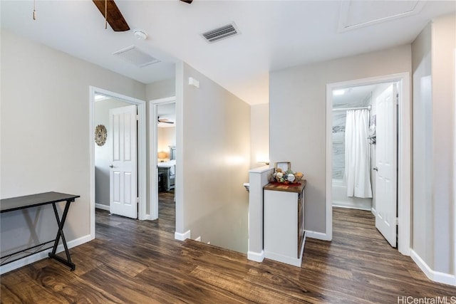 hall featuring visible vents, baseboards, attic access, and dark wood finished floors