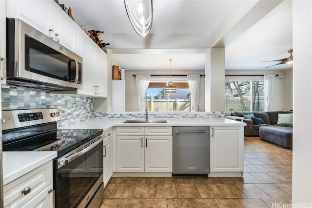 kitchen with stainless steel appliances, white cabinets, a sink, and backsplash