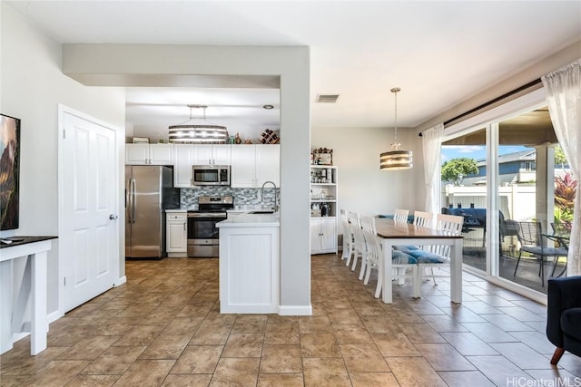 kitchen with tasteful backsplash, visible vents, a sink, appliances with stainless steel finishes, and white cabinetry
