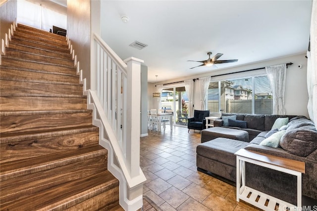tiled living area with ceiling fan, visible vents, and stairway