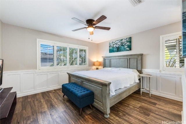 bedroom featuring a ceiling fan, dark wood-style flooring, wainscoting, and visible vents
