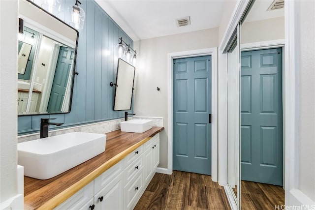bathroom with visible vents, a sink, and wood finished floors