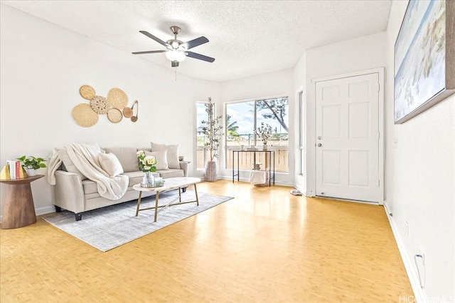 91-490 Puamaeole St Unit 46C, Ewa Beach, HI 96706 - living area with wood finished floors, a ceiling fan, a textured ceiling, and baseboards