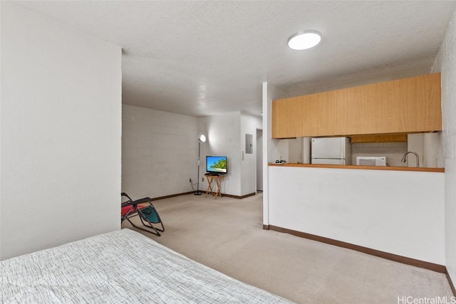 unfurnished bedroom with baseboards, refrigerator, light carpet, a sink, and freestanding refrigerator