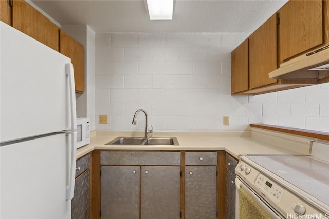 kitchen with white appliances, light countertops, under cabinet range hood, and a sink