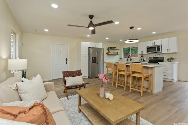 living area with ceiling fan, recessed lighting, plenty of natural light, and light wood-style floors