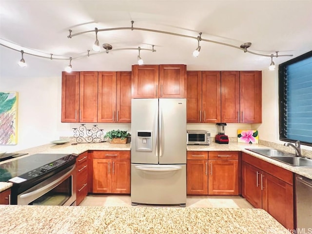 kitchen with a toaster, light stone countertops, stainless steel appliances, and a sink