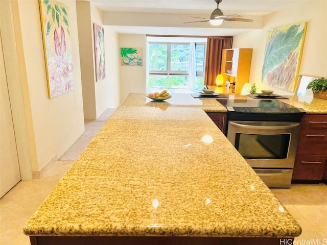 kitchen with light stone countertops, stainless steel range with electric stovetop, and ceiling fan
