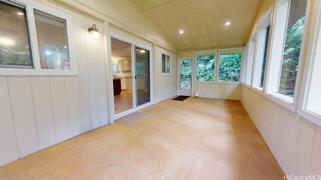 unfurnished sunroom featuring wood walls and lofted ceiling