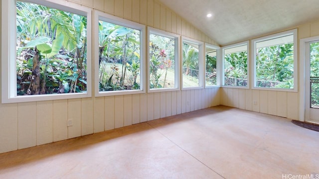 unfurnished sunroom with wood walls, vaulted ceiling, and concrete floors
