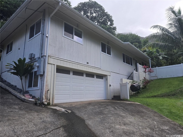 back of house featuring fence, an attached garage, a yard, and driveway