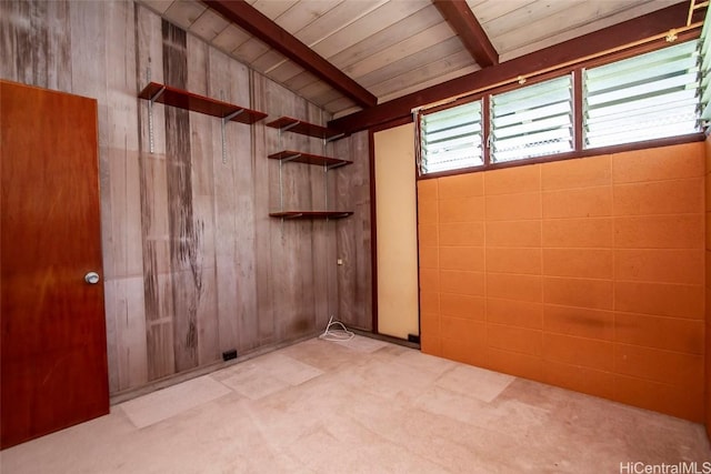 spare room with wood walls, wooden ceiling, and beam ceiling