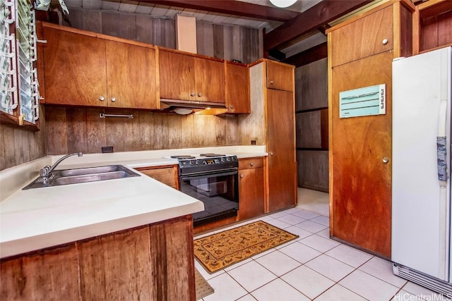 kitchen with light tile patterned flooring, black range with electric stovetop, under cabinet range hood, a sink, and freestanding refrigerator
