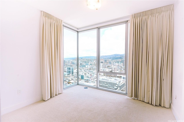 spare room with a wall of windows, a city view, and carpet floors
