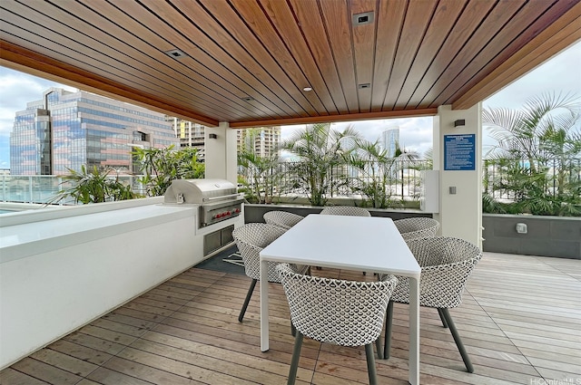 wooden deck with an outdoor kitchen, a view of city, outdoor dining space, and grilling area