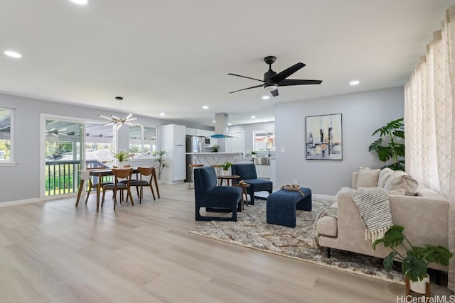 living room featuring baseboards, light wood-type flooring, recessed lighting, and a ceiling fan
