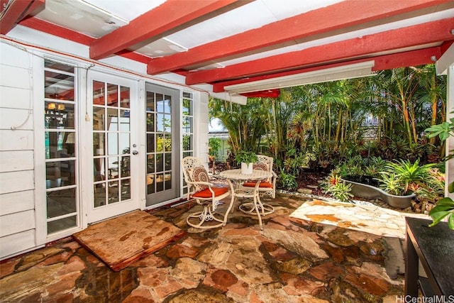 sunroom with stone floors, french doors, and beamed ceiling