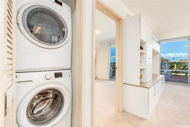 clothes washing area featuring stacked washer / dryer, laundry area, and light carpet