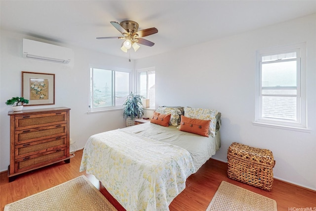 bedroom featuring ceiling fan, a wall mounted AC, and wood finished floors