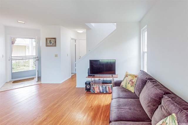 living room with baseboards, stairs, and light wood finished floors