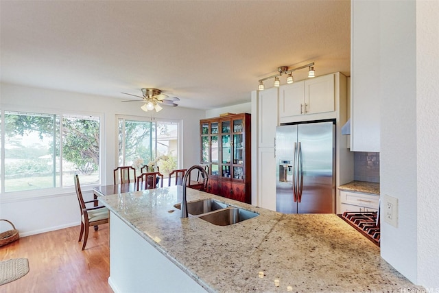 kitchen featuring a sink, stainless steel fridge with ice dispenser, white cabinets, ceiling fan, and light stone counters