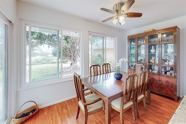 dining area with baseboards, light wood-style floors, and a ceiling fan