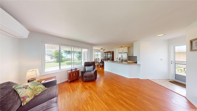living room featuring light wood finished floors, a wall mounted air conditioner, and baseboards