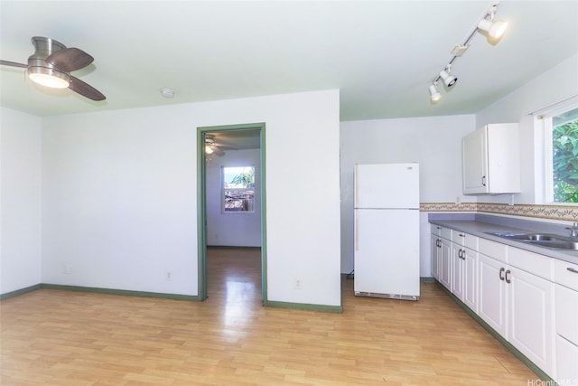 87-118 Alapaki St, Waianae, HI 96792 - kitchen with freestanding refrigerator, light wood-type flooring, ceiling fan, and white cabinetry