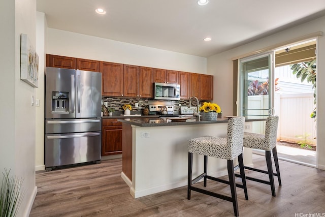 91-6221 Kapolei Pkwy Unit 511, Ewa Beach, HI 96706 - kitchen with stainless steel appliances, dark countertops, wood finished floors, backsplash, and a kitchen bar
