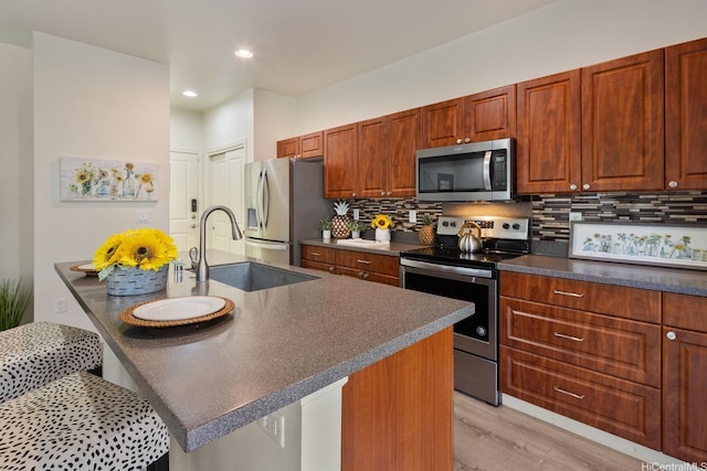 91-6221 Kapolei Pkwy Unit 511, Ewa Beach, HI 96706 - kitchen featuring appliances with stainless steel finishes, a sink, dark countertops, light wood-style floors, and decorative backsplash