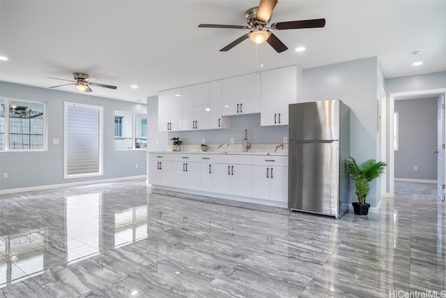 kitchen with light countertops, baseboards, ceiling fan, white cabinetry, and freestanding refrigerator