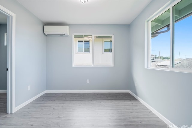 spare room with a wall unit AC, baseboards, and wood finished floors