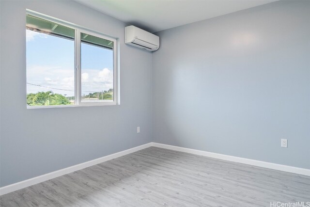 unfurnished room with baseboards, wood finished floors, and a wall unit AC