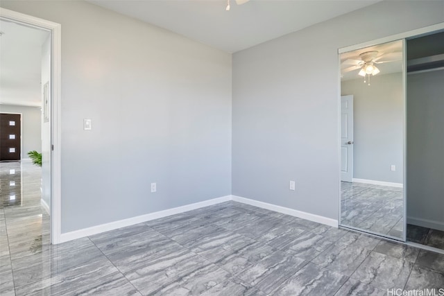 unfurnished room with marble finish floor, a ceiling fan, and baseboards