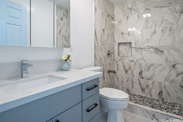 bathroom with toilet, vanity, and a tile shower