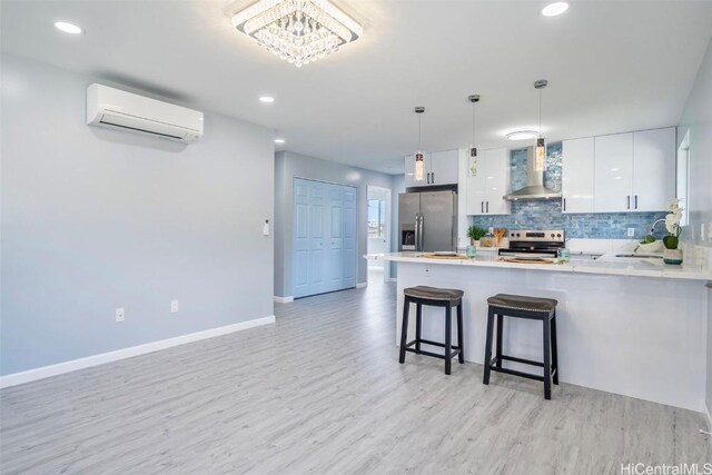 kitchen featuring tasteful backsplash, stainless steel appliances, an AC wall unit, wall chimney range hood, and a peninsula