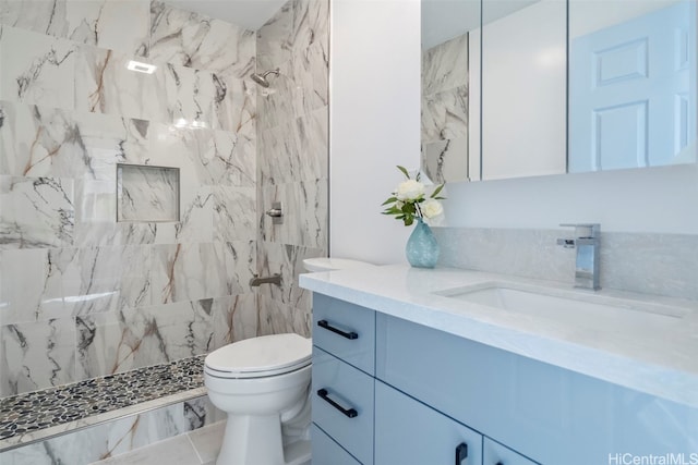 full bathroom with a tile shower, toilet, and vanity